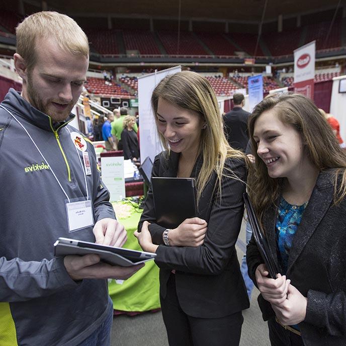 Two students talk with a Workiva company recruiter at a career fair