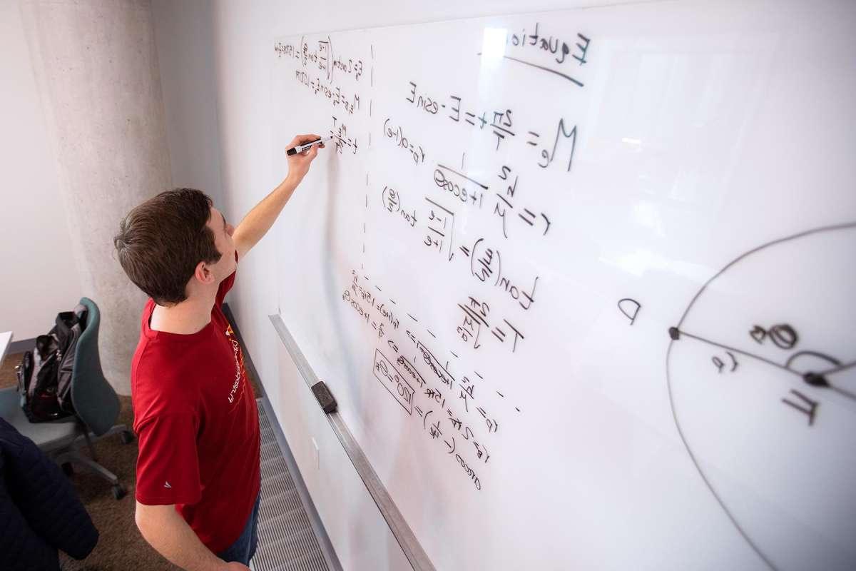 A student writing equations on a whiteboard
