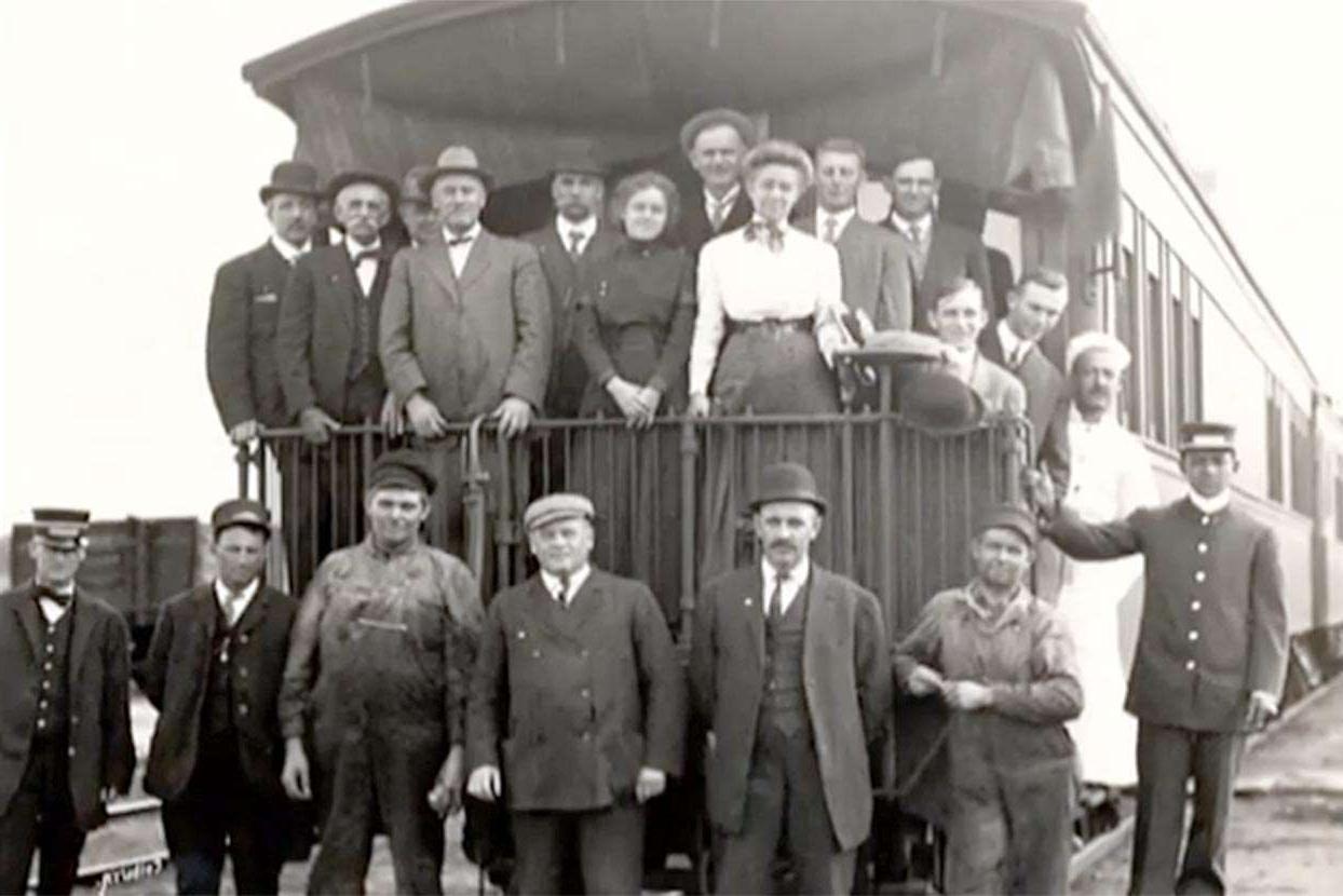 一个早期旅行扩展组在火车车尾摆姿势的黑白照片存档